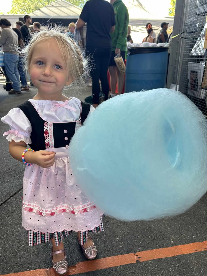 Girl in a dirndl dress with blue cotton candy