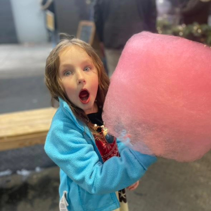 Girl with a surprised expression holding pink cotton candy
